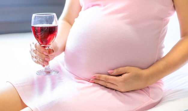 Kobieta w ciąży trzyma kieliszek wina
