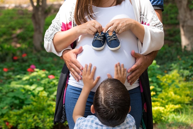 Kobieta w ciąży trzyma na brzuchu buciki dziecka.