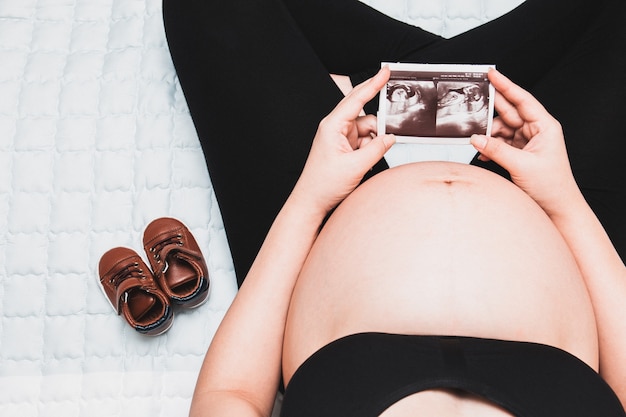 Kobieta w ciąży trzyma obraz USG. Matka czeka na dziecko.