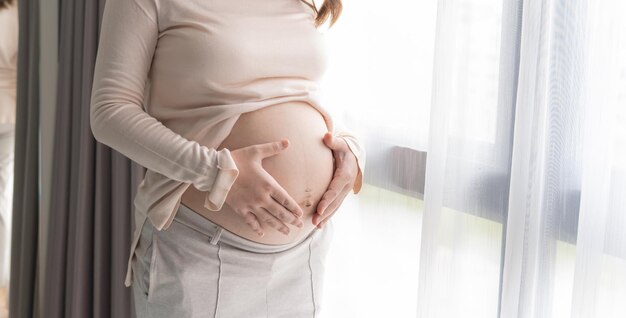 Kobieta w ciąży trzyma ręce na brzuchu dotykając swojego dziecka dbając o swoje zdrowie Piękna szczęśliwa kobieta w ciążu delikatny nastrój zdjęcie ciąży