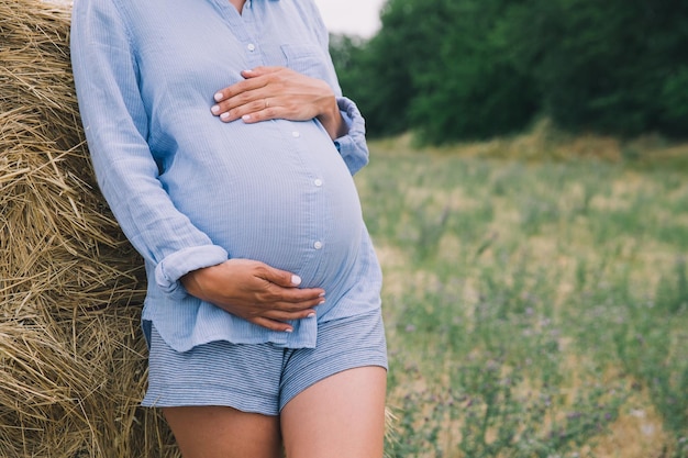 Zdjęcie kobieta w ciąży trzyma ręce na brzuchu na tle przyrody na świeżym powietrzu