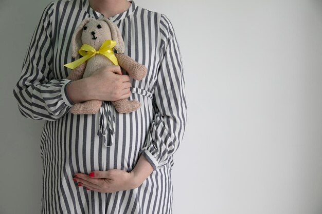 Kobieta w ciąży trzymająca brzuszek i pluszowego królika