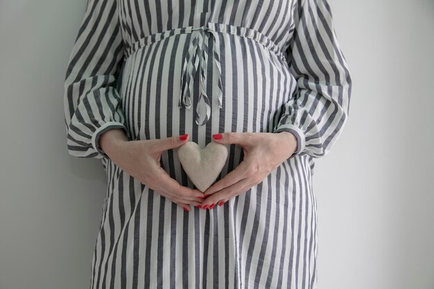 Kobieta w ciąży trzymająca kształt serca przed brzuszkiem