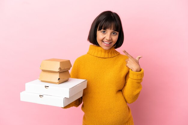 Kobieta W Ciąży Trzymająca Pizze I Hamburgery Na Białym Tle Na Różowym Tle Dająca Gest Kciuka W Górę