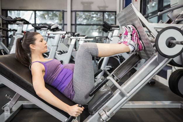 Kobieta w ciąży używa ciężar maszynę przy gym