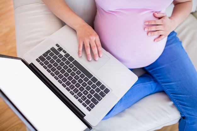 Kobieta w ciąży używa jej laptop
