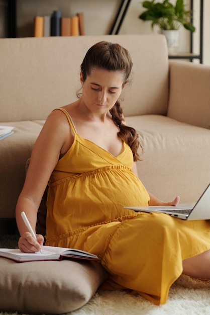 Kobieta w ciąży używa laptop w domu