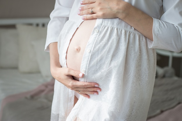 Zdjęcie kobieta w ciąży w białej koszuli przytula jej brzuch