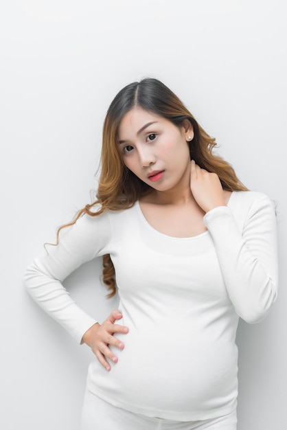 Kobieta w ciąży w białej sukni, trzymająca się za brzuch