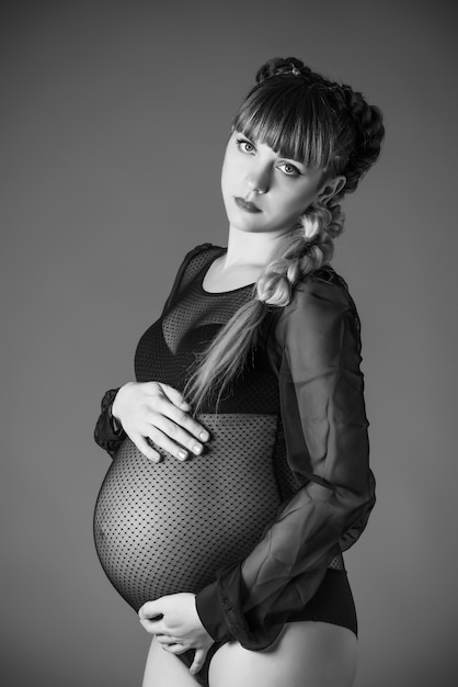 kobieta w ciąży w czarnym Body, trzymając jej brzuch