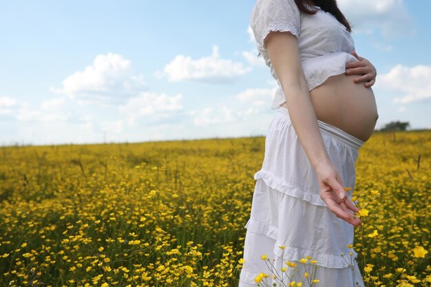 Kobieta w ciąży w sukience na polu kwiatów