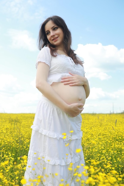 Kobieta w ciąży w sukience na polu kwiatów
