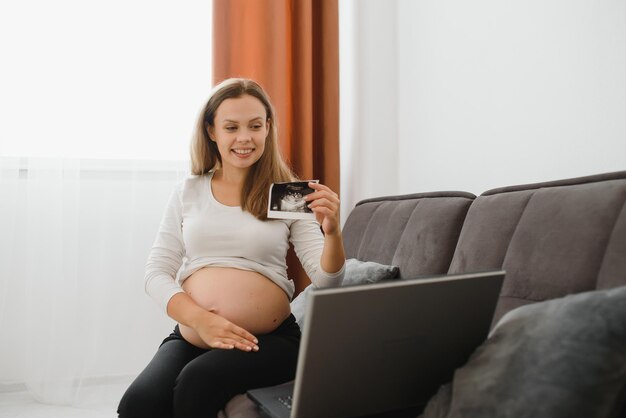 Kobieta w ciąży wideo na czacie z lekarzem na laptopie. Koncepcja profesjonalnych konsultacji medycznych online.