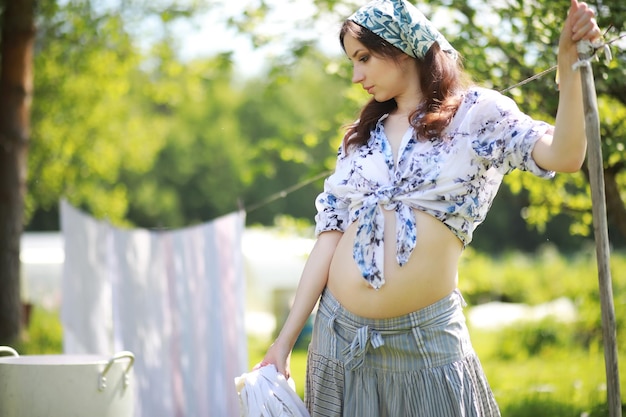 Zdjęcie kobieta w ciąży wiesza pranie na linie do suszenia