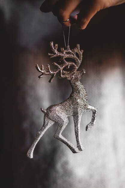 Kobieta w ciepłym swetrze trzyma zabawka jelenia szkła ozdobna kula w ręce, miejsce. Boże Narodzenie, koncepcja obchodów święta nowego roku