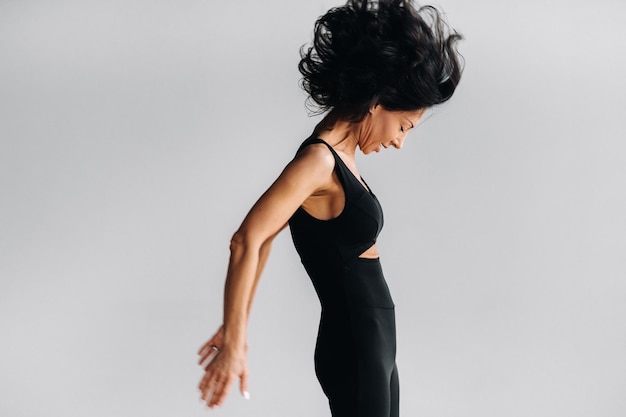 Kobieta w czarnym stroju sportowym zajmuje się dynamiczną medytacją kali w sali jogi