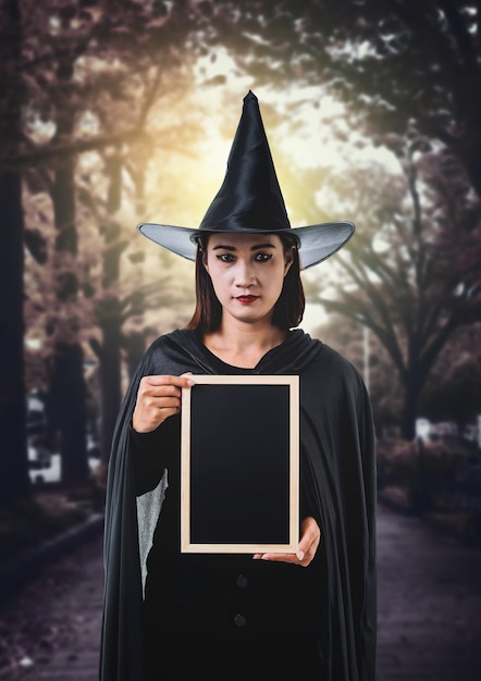 Kobieta w czerni Straszny czarownica Halloween kostium, Trzymający kredową deskę z blaskiem księżyca w ciemnym celu
