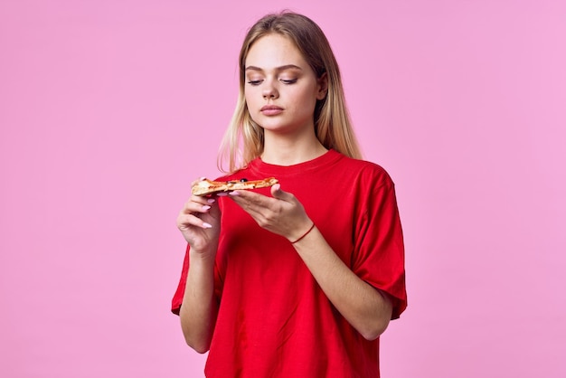 Kobieta w czerwonej koszulce, przekąska fast food, różowe tło, zdjęcie wysokiej jakości.