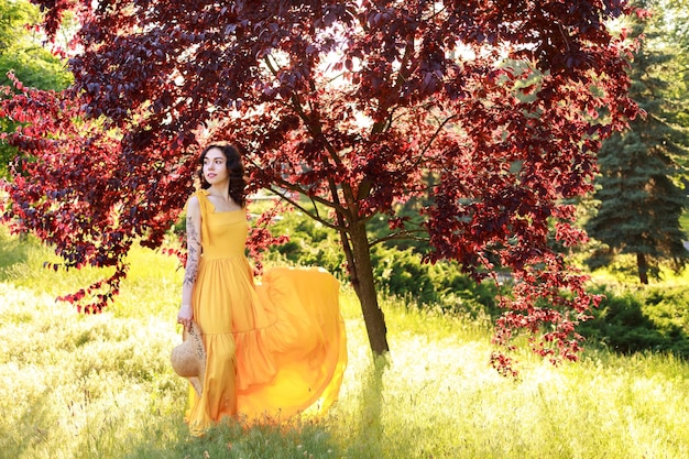 Kobieta w długiej letniej sukience z mahoniu w ogrodzie na pocztówce spaceru