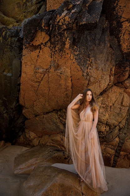 Kobieta w długiej sukni w pobliżu skał i oceanu