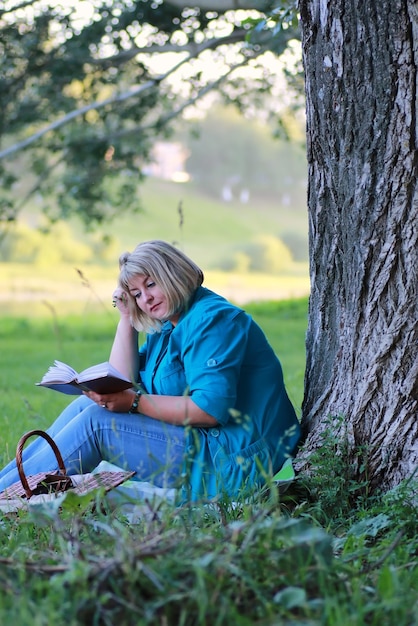 Kobieta w drzewie parkowym czyta książkę