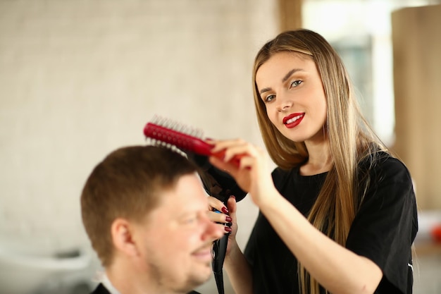 Kobieta w fryzjerze fryzjer robi fryzurę z suszarką do włosów dla męskiego klienta