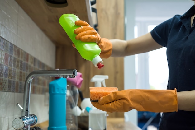 Kobieta w gumowych rękawiczkach do czyszczenia brudnej powierzchni w kuchni