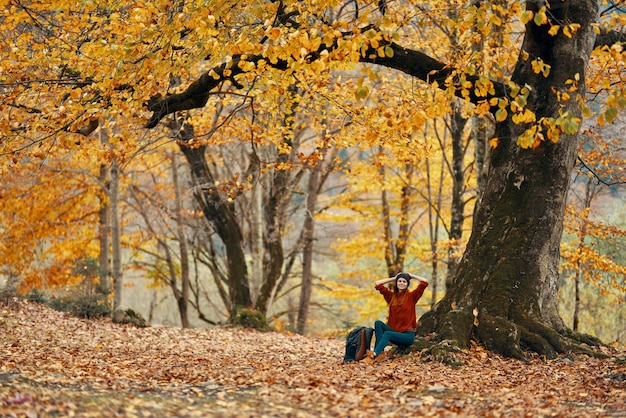 Kobieta w jesieni w lesie siedząca pod drzewem krajobraz żółtych liści model wysokiej jakości zdjęcie