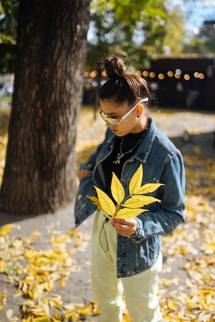 Kobieta w jesiennym parku trzyma żółty liść