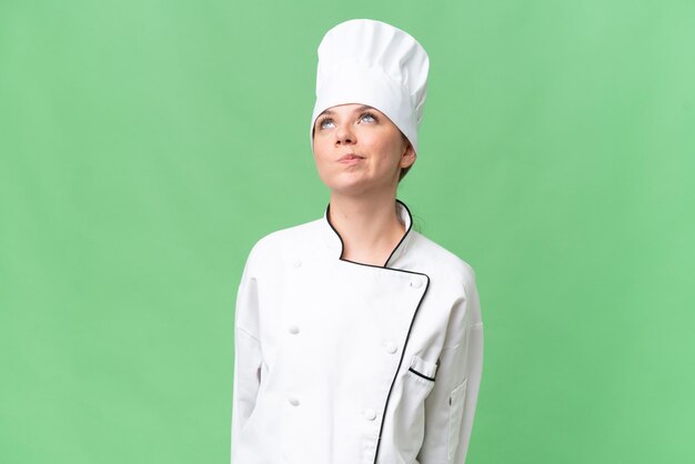 Zdjęcie kobieta w kapeluszu szefa kuchni patrzy na zielony ekran.