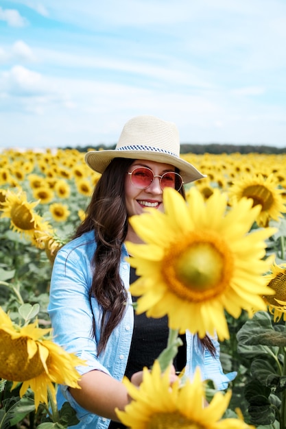 Kobieta w kapeluszu w polu słoneczników ciesząca się przyrodą