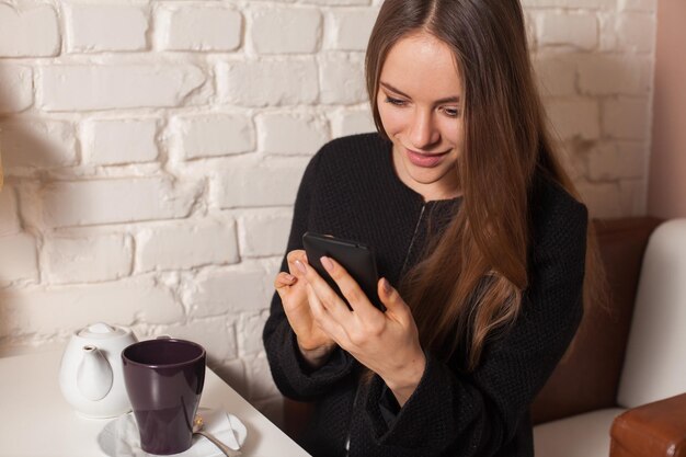 Zdjęcie kobieta w kawiarni pije herbatę i używa swojego smartfona