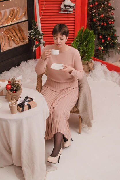 Kobieta w kawiarni pije kawę lub herbatę. Koncepcja Bożego Narodzenia i Nowego Roku.