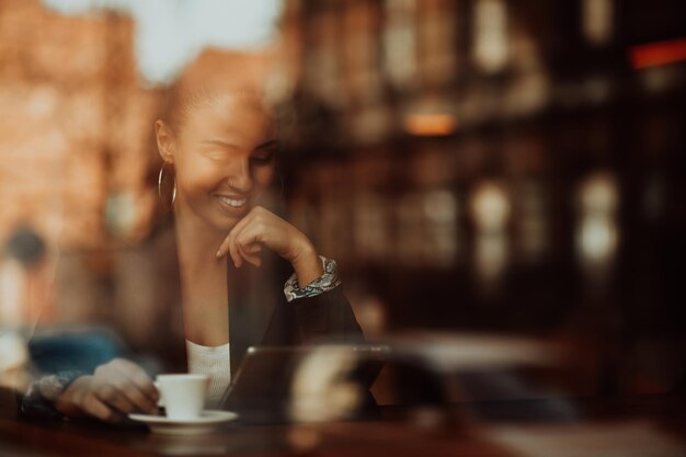 kobieta w kawiarni pije kawę oglądaną przez szkło z odbiciami, gdy siedzą przy stole, rozmawiając i śmiejąc się