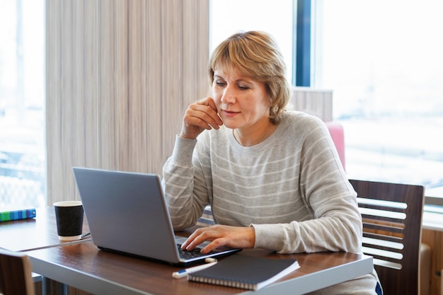 Kobieta w kawiarni pracuje na laptopie. Pojęcie biznesu i pracy zdalnej.