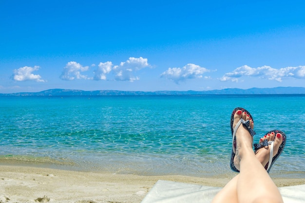 Kobieta w klapkach leżąca na leżaku w pobliżu oceanu na plaży