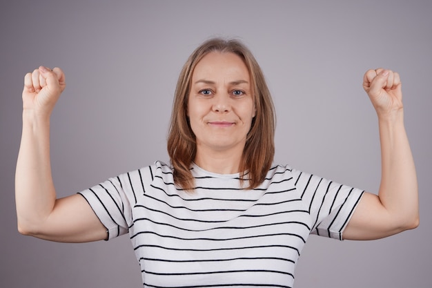 kobieta w koszuli w paski pokazuje bicepsy na ramieniu