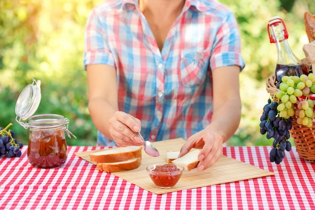 Kobieta w kraciastej koszuli rozrzuca dżem na chleb