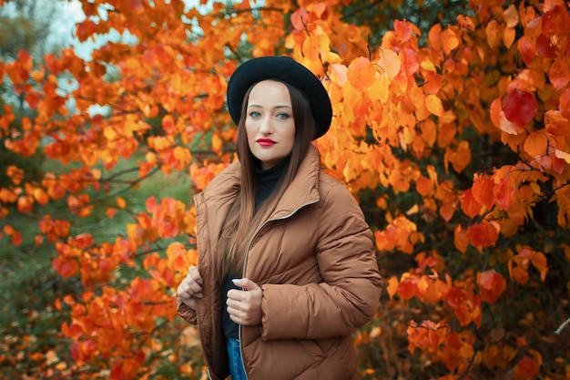 kobieta w kurtce i kapeluszu jesienią w parku