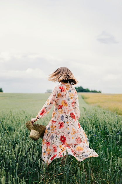 Kobieta w kwiecistej sukience z tkanym kapeluszem na polu