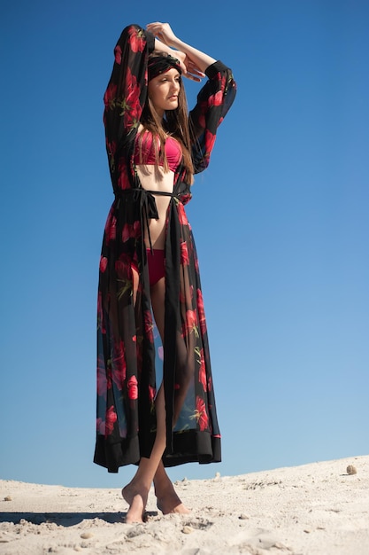 Kobieta w kwiecistym kimonie stoi na wzgórzu z niebem za nią.