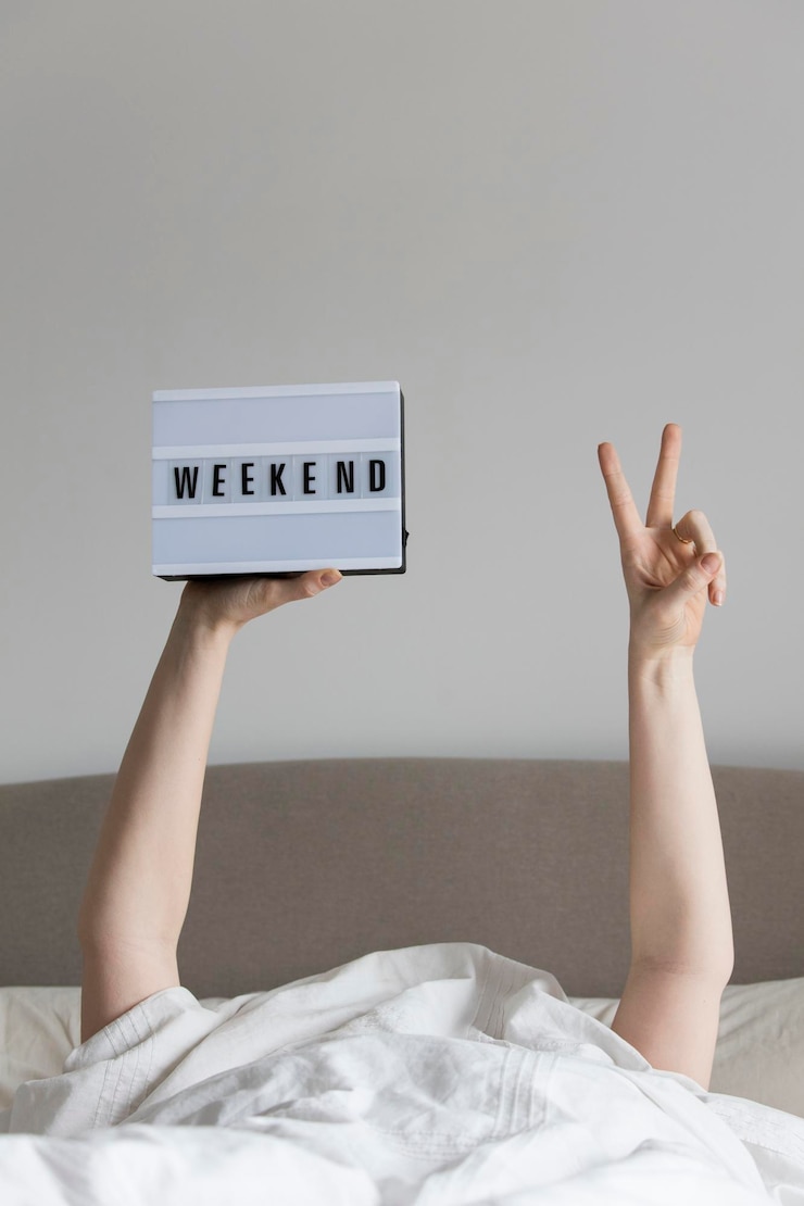Zdjęcie kobieta w łóżku pod prześcieradłem trzymająca znak weekendu