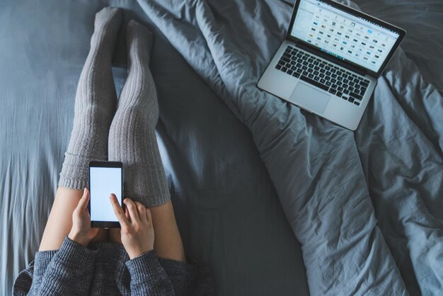 Kobieta w łóżku przy użyciu surfowania po internecie za pomocą smartfona.