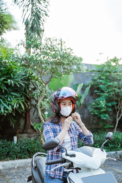 Kobieta w masce wiążąca pasek zabezpieczający kask przed jazdą na motocyklu