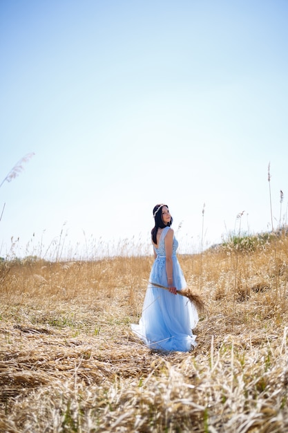 Kobieta w niebieskiej długiej sukni w trzcinach. Moda portret z suszonymi kwiatami