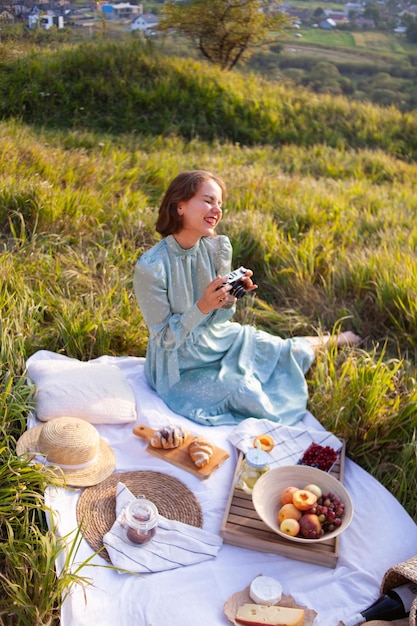 Kobieta w niebieskiej sukience siedzi na pikniku w parku z panoramicznym widokiem