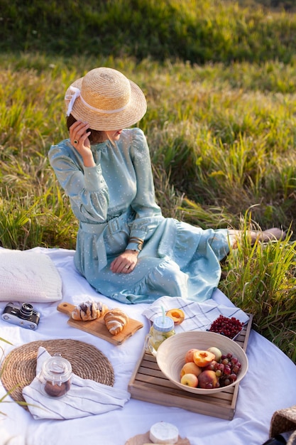 Kobieta w niebieskiej sukience siedzi na pikniku w parku z panoramicznym widokiem