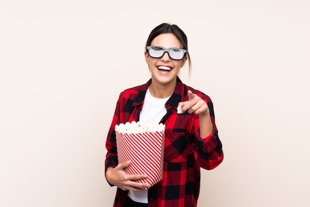 Kobieta w okularach 3d i gospodarstwa duże wiadro popcorns, wskazując z przodu