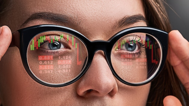 Zdjęcie kobieta w okularach patrzy na notowania giełdowe i kursy walut podczas kryzysu finansowego