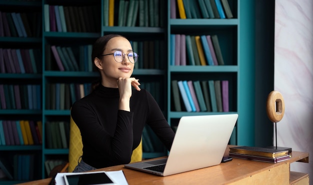 Kobieta w okularach, prawnik pracuje w biurze, korzysta z laptopa i drukuje wiadomość na pocztę